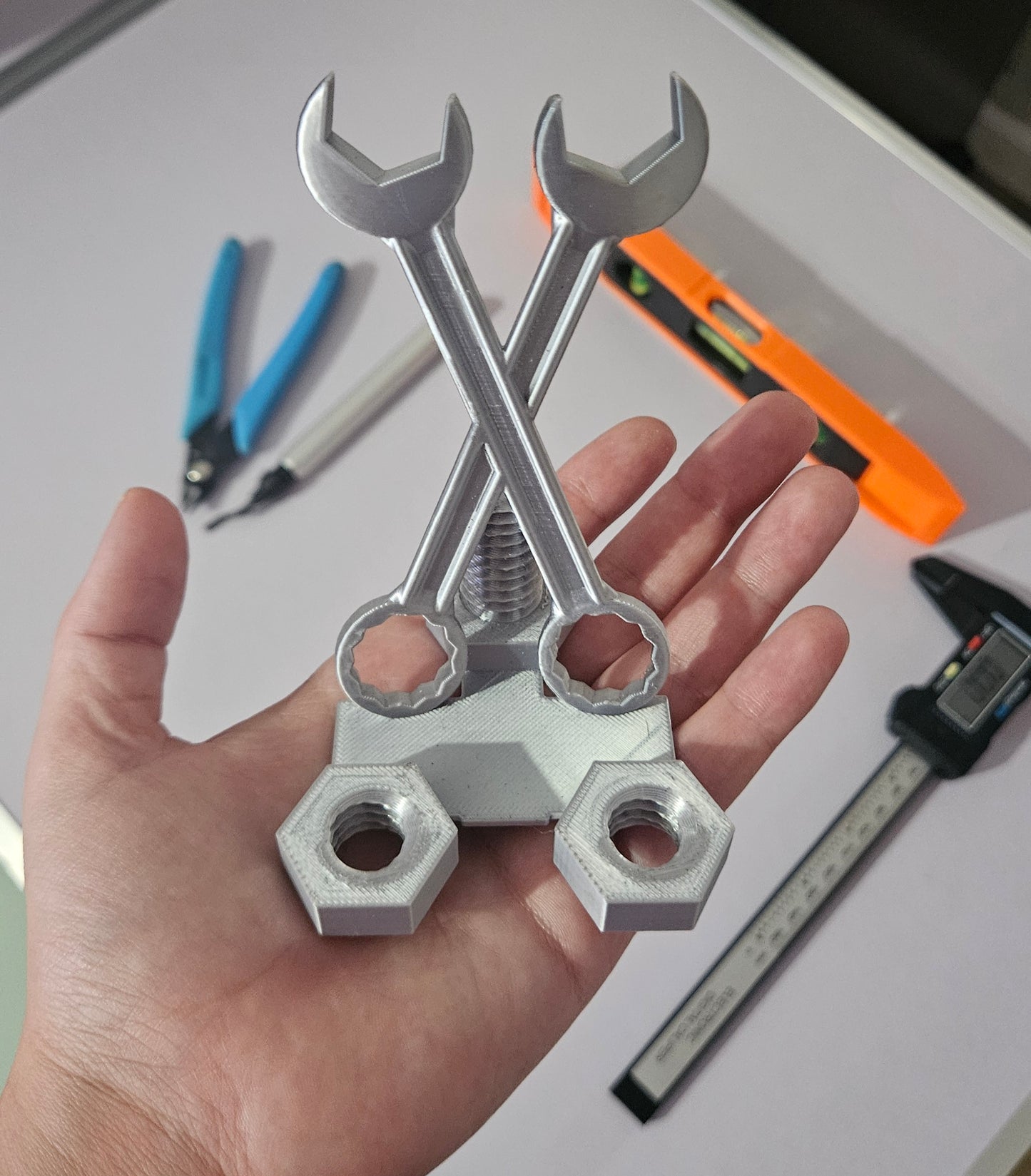 Metal wrenches and nuts held in a hand with tools in the background