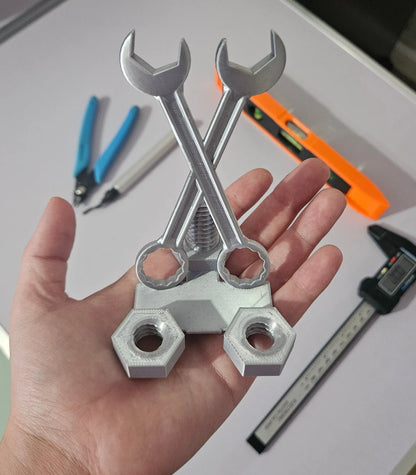 Metal wrenches and nuts held in a hand with tools in the background