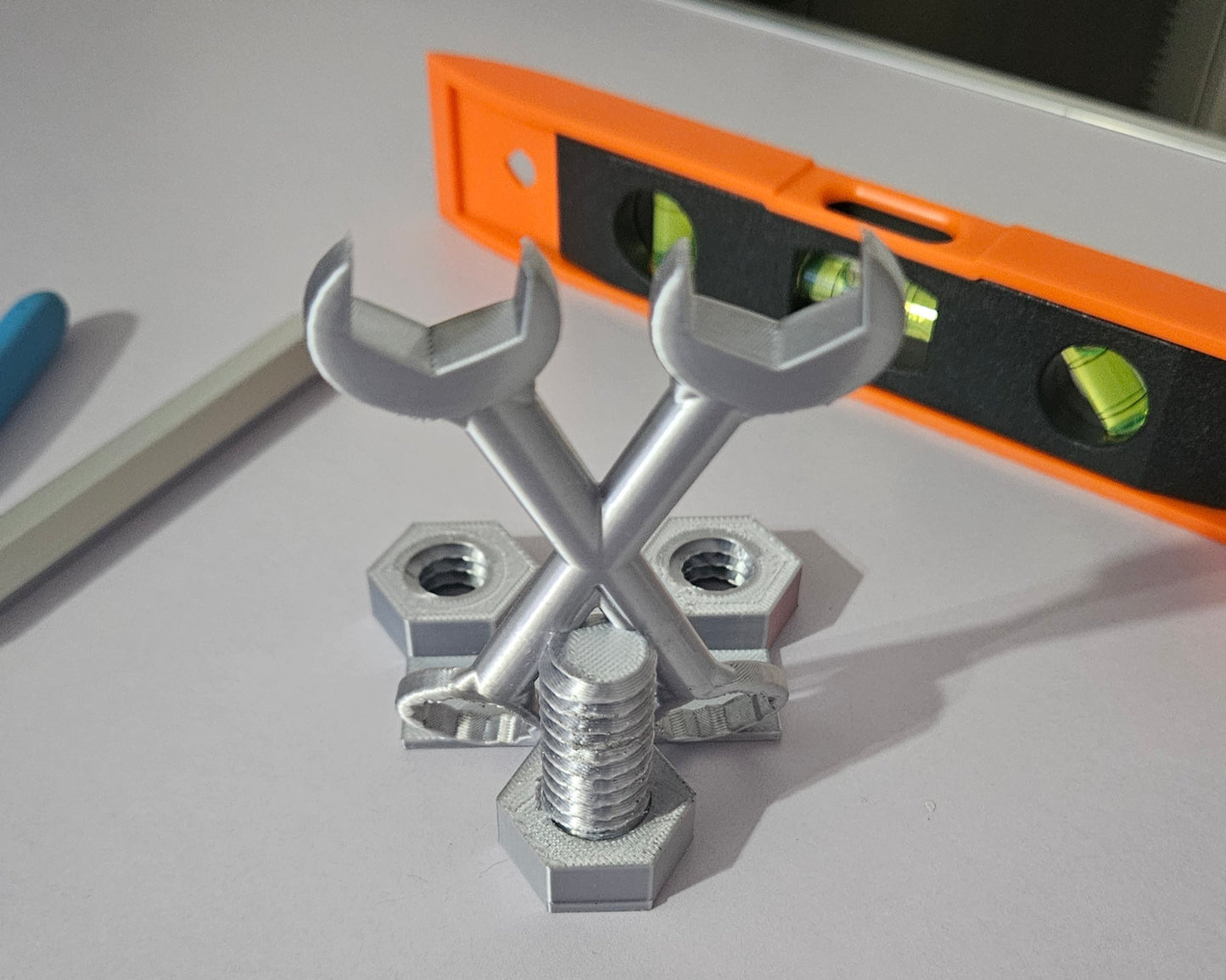 Metal wrenches and nuts on a gray surface with an orange level in the background
